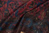 Mehreban rug corner, showing raspberry red, sapphire blue floral cross-sections and machine binding.