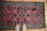 Pale raspberry Lilihan rug with allover blue and ivory blossoms, showing shoes.
