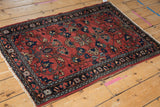Vintage Lilihan rug corner detail: brick red field, intricate floral motifs, navy border.