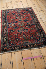 Corner detail of a Vintage Lilihan rug with brick red field, navy floral motifs, and fringe.