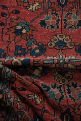 Close-up of folded Lilihan rug showcasing brick red field, sapphire blue palmettes, and blossoms.