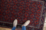 A close view of the fine Engelas rug's plush wool pile and allover Herati design in rust and navy blue.