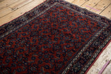 High-angle view of the vintage Engelas rug's plush, rust-red pile and dense navy Herati motif.