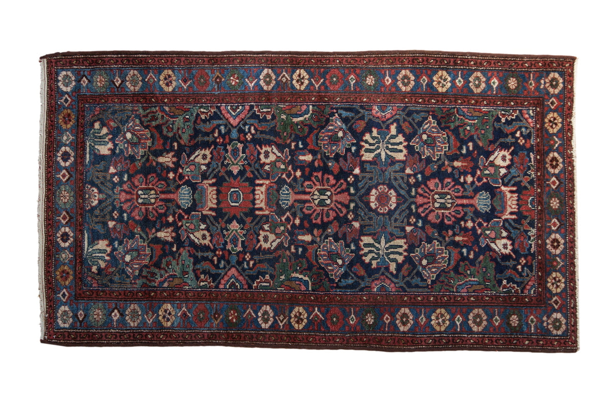 Vintage Mehreban rug with an allover field of floral blossoms in red, teal, and green on a navy blue ground.