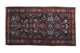 Vintage Mehreban rug with an allover field of floral blossoms in red, teal, and green on a navy blue ground.