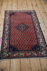 Corner of a Persian Engelas rug showcasing madder red boteh field and ivory floral border.