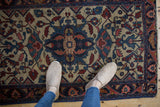 Vintage Lilihan rug's sapphire blue and cochineal red floral field, with white shoes.