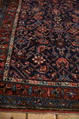 Angled close-up of vintage Kurdish Hamadan rug, with navy Herati design and madder red border.
