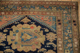 Corner detail of vintage Malayer rug: navy field with stylized serpents, textured pile, blush borders.