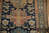 Malayer rug border with geometric motifs in blue, sand, and blush, showing frayed selvage.
