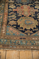 Malayer rug's hand-knotted border, navy, sand, and blush motifs, with frayed fringe.