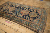 Corner of a vintage Malayer rug with frayed fringe, worn selvage, and patterned borders.