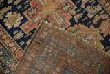 Vintage Malayer rug corner folded, revealing detailed blush and navy border motifs.