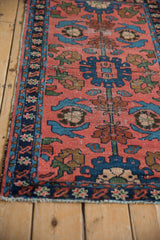 Tattered edge and worn pile of vintage Lilihan rug in brick red and indigo.