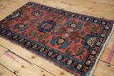 Detail of Lilihan rug: dusty faded brick red field, blue floral patterns, wear to knot heads.