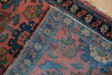 Dusty faded brick red field with blue motifs showing mostly even wear on knot heads.