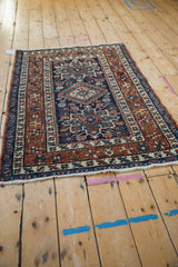Vintage Karaja rug corner with chestnut starburst border, navy field, and intact white fringe.