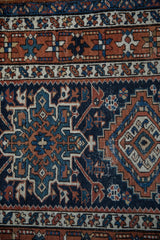 Vintage Karaja rug detail: navy geometric motifs, starburst border, and mostly even wear.