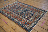 Karaja rug corner: starburst border, geometric motifs in navy, chestnut, ivory, and intact selvage.