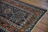 Vintage Karaja rug corner detail, highlighting navy, copper, ivory geometric patterns and short fringe.