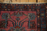 Lilihan rug end showing dusty cochineal field, blue blossoms, and visible knot heads.
