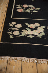 Close-up of vintage Romanian Kilim's ivory fringe, thin line, and mauve blossoms.