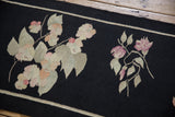 Close-up of hand-woven black Kilim runner with dusty mauve blossoms and ivory leaves.