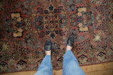 Vintage Sarouk rug with allover floral design in dusty rose and navy, shown with feet.