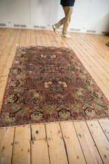 Hand knotted vintage Sarouk rug corner with dusty rose, navy floral motifs and fringe.