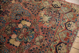 Vintage Sarouk rug corner: dusty rose field, blue florals, ornate border, frayed edge.