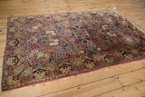 Vintage Persian Sarouk corner, intricate floral border, dusty rose field, and fringe.