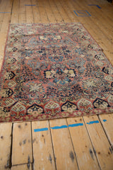 Vintage Sarouk rug's dusty rose field features navy floral bouquet and intact side selvage.