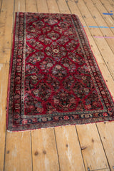 Corner of Vintage American Sarouk rug runner, cherry red floral field, patterned borders, and edge tatter.