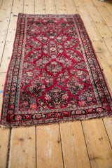 Corner of vintage American Sarouk runner, cherry red floral design, and tattered edge.