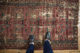 Vintage Persian Mehreban rug, worn texture, dusty plum and teal arabesques, with feet for scale.