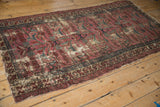 Tattered corner of vintage Mehreban rug, with worn dusty plum field and teal vine border.