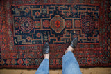 Vintage Kurd rug's navy blue field with brick red geometric medallions and intricate patterns.