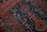 Navy blue field with brick red geometric stepped medallions on vintage Kurd rug, showing even pile wear.