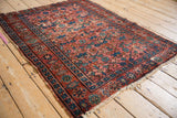 Vintage Persian Lilihan rug with tattered ends, worn raspberry, indigo, and green lattice blossoms.