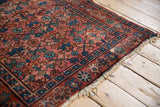 Corner detail of the Lilihan rug with triple column plant pattern, indigo blue border, and worn fringe.