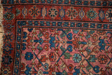 Close-up Lilihan rug: triple column germinating plants, indigo and raspberry tones, visible wear.