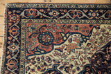 Antique Farahan Sarouk rug corner detail: ivory field with floral vinery, navy arabesque border.