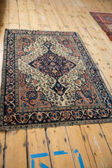 Navy main border with vibrant palmettes and arabesques on antique Farahan Sarouk rug's ivory floral field.