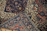 Folded corner of antique Farahan Sarouk rug revealing blue palmette border and hand-knotted foundation.