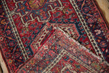 Folded vintage Karaja rug, showing hand-knotted reverse, cherry red patterns, and mostly even wear.
