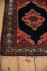 Angled view of a vintage Malayer rug corner showing the geometric border and original selvage.