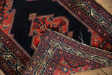 A folded corner on a vintage Malayer rug reveals the hand-knotted weave and original side cord.