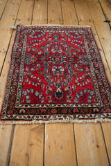 Corner of vintage Persian Lilihan rug mat, cherry red field with floral motifs, intact selvage.