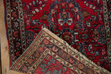 Hand-knotted vintage Lilihan rug folded, revealing original selvage, fringe, and red floral pattern.