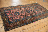 Vintage Lilihan rug corner: tattered fringe, blush pink field, blue borders, serrated palmettes.
